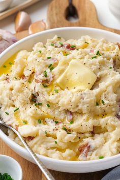 mashed potatoes with ham and parsley in a white bowl on a wooden cutting board