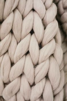 a close up view of the texture of a knitted object in light pink tones