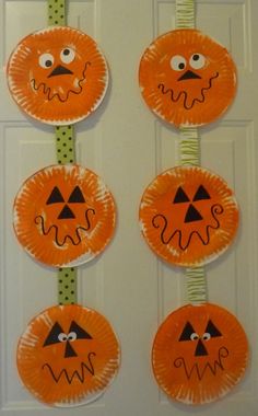 paper plate pumpkins with faces on them hanging from the front door for halloween decorations