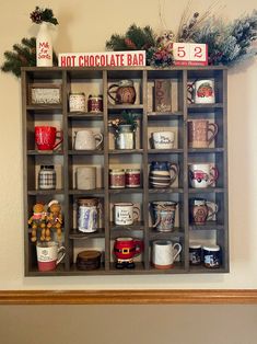 a wooden shelf filled with lots of coffee mugs and christmas decorations on top of it