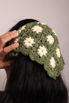 a close up of a person wearing a crocheted hat with flowers on it