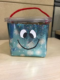 a plastic container with a face painted on the side and snowflakes around it