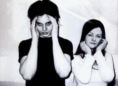 two people standing next to each other with their hands on their faces