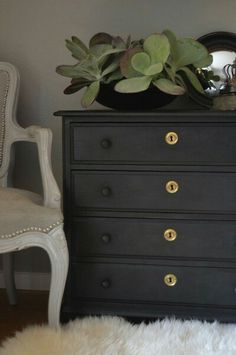 a black dresser with gold knobs and plants on top