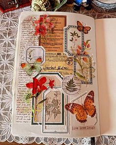 an open book with butterflies and flowers in it on a lace doily covered table