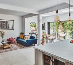 an open concept living room and dining area with blue couches, orange chairs, and white marble countertops