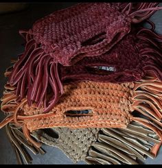 three woven purses are stacked on top of each other, one is brown and the other is red