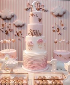 a pink and white wedding cake with gold stars on top, surrounded by other desserts