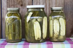 three jars filled with pickles sitting on top of a table