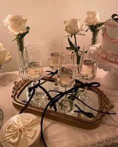 there are many wine glasses on the table with cake and flowers in vases behind them