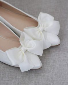 a pair of white shoes with a large bow on the front and bottom of them