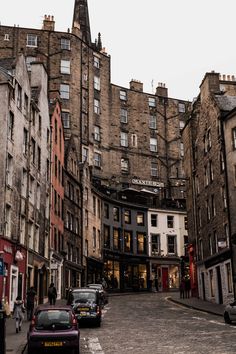 cars are parked on the street in front of tall buildings