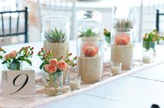 there are many vases with flowers and plants in them on the table at this wedding reception