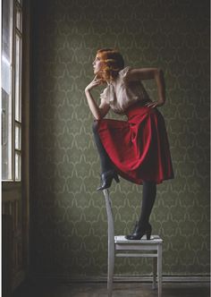 a woman sitting on top of a chair in front of a window