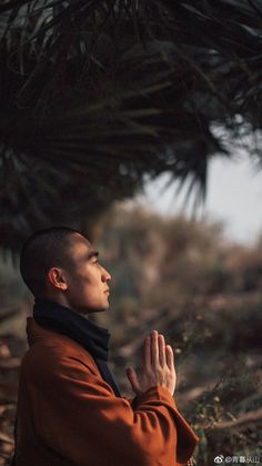 a man standing in front of a pine tree with his hands clasped to the ground