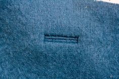 a piece of blue wool with a small hole in the middle that has been stitched into it