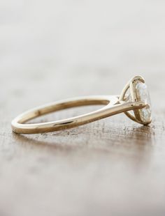 a yellow gold engagement ring with a single diamond in the center on a wooden surface