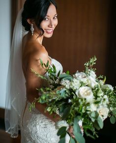 a woman in a wedding dress holding a bridal bouquet and smiling at the camera