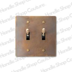 an antique brass double switch plate with two black knobs and one white light switch