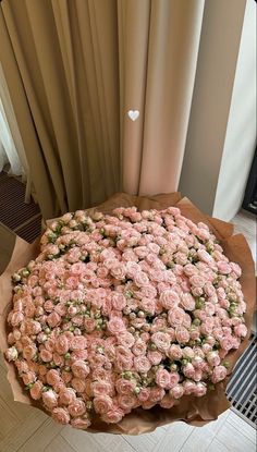 a large bouquet of pink roses sitting on top of a wooden table next to a window