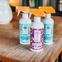 three bottles of cleaner sitting on top of a wooden table