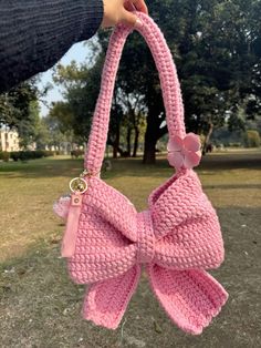 a hand holding a pink crocheted bow purse