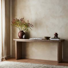 a wooden table with two vases and a bowl on it next to a window