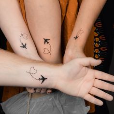 three people are holding their hands together with small tattoos on their arms and wristes