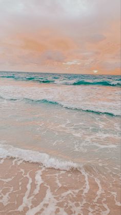 an ocean beach with waves coming in to shore and the sun setting over the horizon