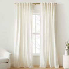 a white curtain hanging in front of a window with the words west elm on it