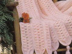 a crocheted blanket with tassels and flowers on it sitting on a chair