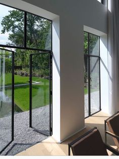 an empty living room with large windows and sliding glass doors that open onto the lawn