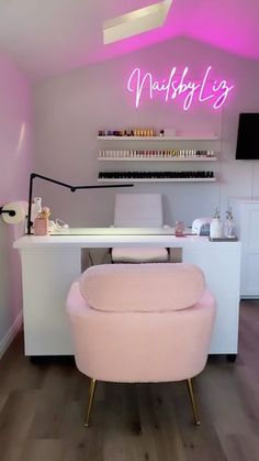 a pink chair sitting in front of a desk with a neon sign on the wall