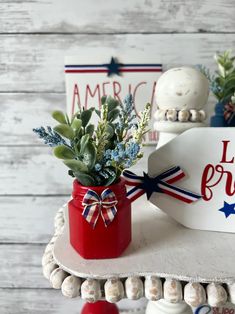 a red vase with flowers on top of a table