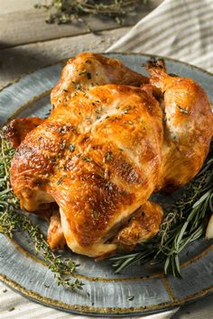 a roasted chicken on a plate with herbs