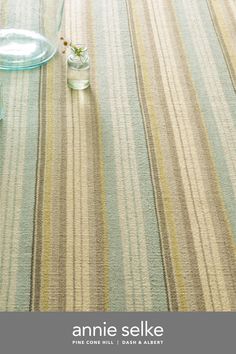 the table is covered with striped linens and glass vases on top of it