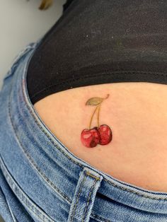 a small cherry tattoo on the back of a woman's stomach