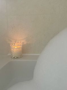 a candle sitting on top of a bath tub next to a white bubble bathtub