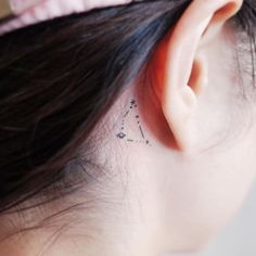 a woman's left ear has a small star tattoo on it