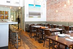 a restaurant with wooden tables and stools in front of a brick wall that has been painted white