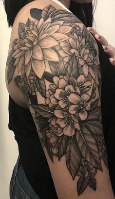 a woman's arm with flowers and leaves tattooed on the back of her shoulder