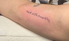 a woman with a tattoo on her arm that says lead with emptyness in cursive writing