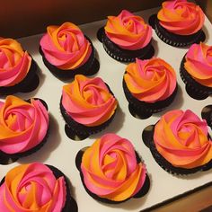 cupcakes with pink and orange frosting in a box