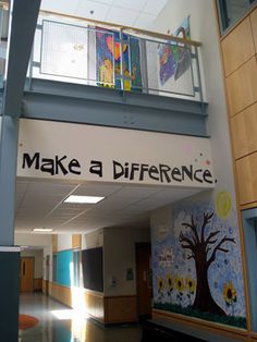 the inside of a school hallway with painted murals on the wall and stairs leading up to the second floor