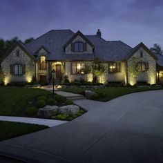 a house that is lit up at night with lights on the front and side of it