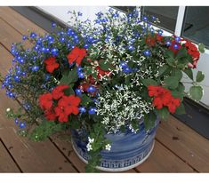 red, white and blue flowers in a pot on a porch