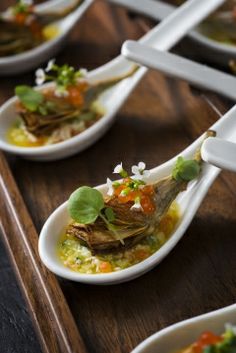 several spoons filled with food on top of a wooden table