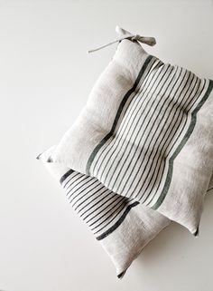 two white and green striped pillows sitting on top of each other next to one another