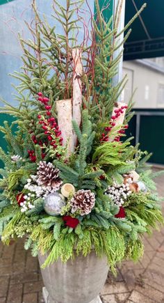 a potted plant with pine cones and evergreens on the outside, in front of a building