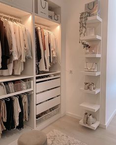 a white closet filled with lots of clothes and shoes next to a wall mounted shelving unit